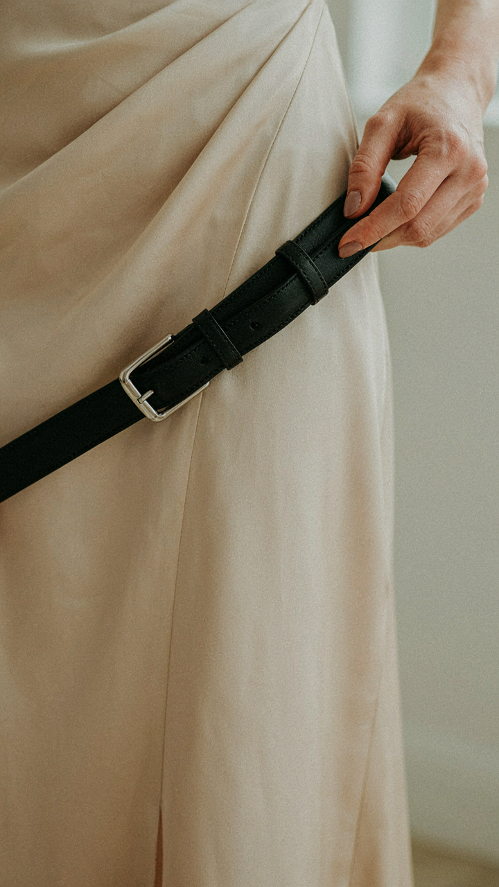 A hand holds a belt against a flowing dress, showing incompatibility.