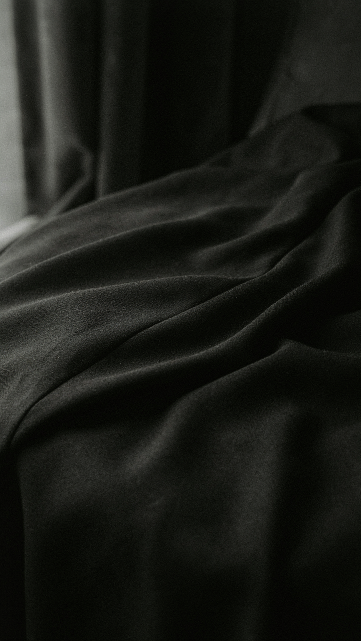 A close-up of a black gown's fabric shows subtle tonal shifts.
