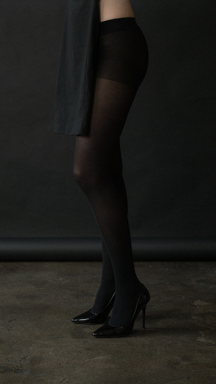 Black opaque tights and black high heels create a long leg line with a mini dress.