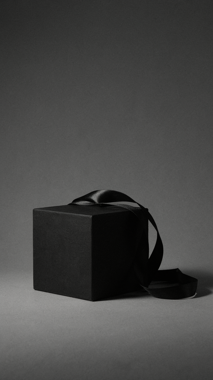 Black satin ribbon draped over a matte black cube.