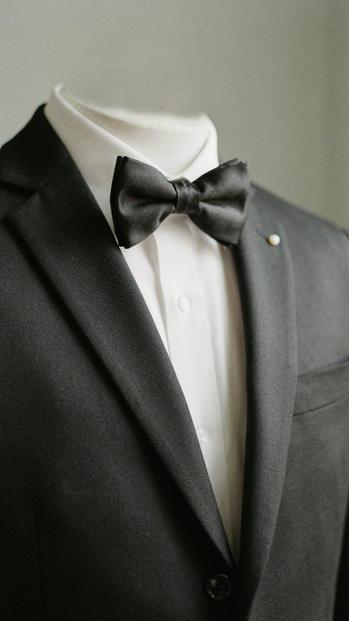 A close-up of a classic black tuxedo jacket, white shirt, and bow tie.