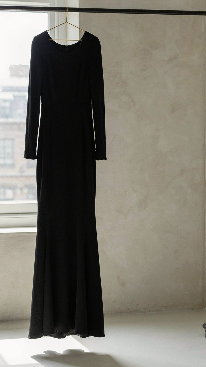 A black column gown in crepe fabric hangs elegantly on a rack.