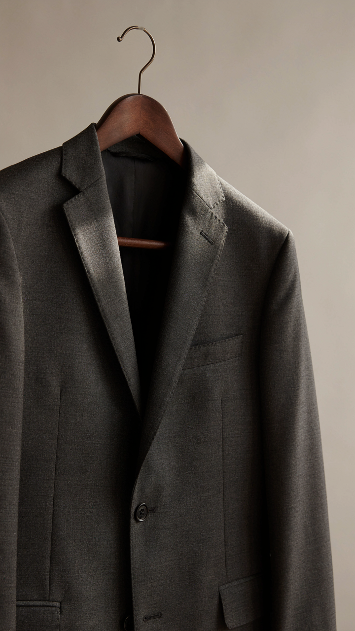 Close-up of a perfectly tailored blazer on a hanger, highlighting its construction.