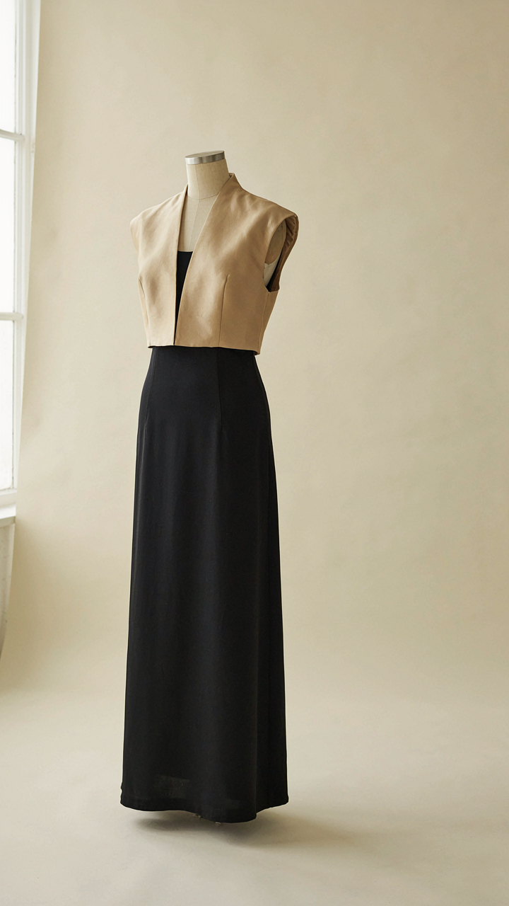 A tailored satin bolero jacket sits at the waist of an evening dress on a mannequin.