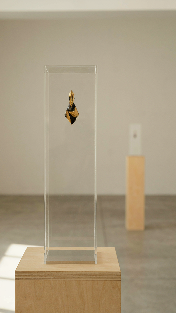 A single geometric drop earring displayed in a minimalist gallery.