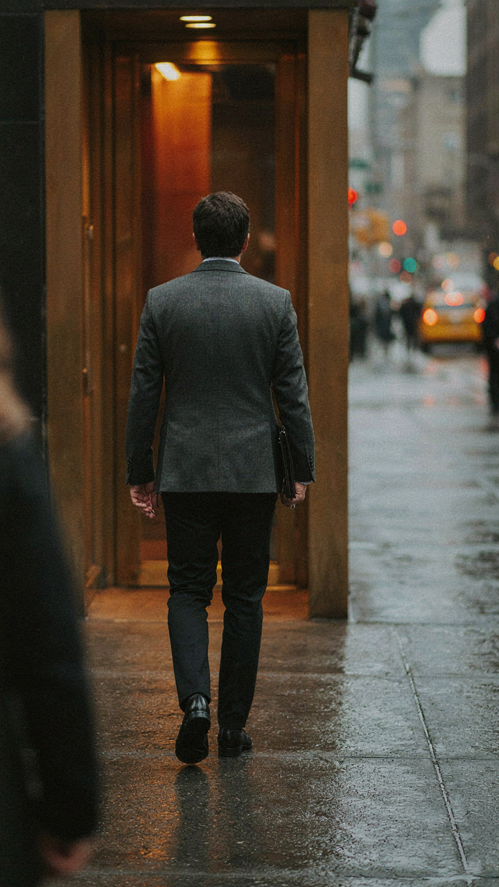 A professional walks away from a restaurant, jacket in place, maintaining a composed posture.