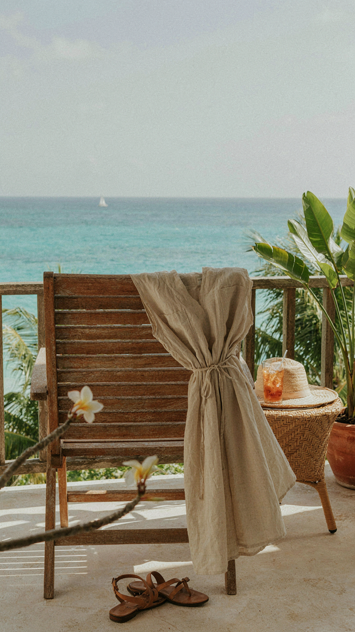 A wrinkled linen-cotton blend dress sits on a chair on a tropical balcony.