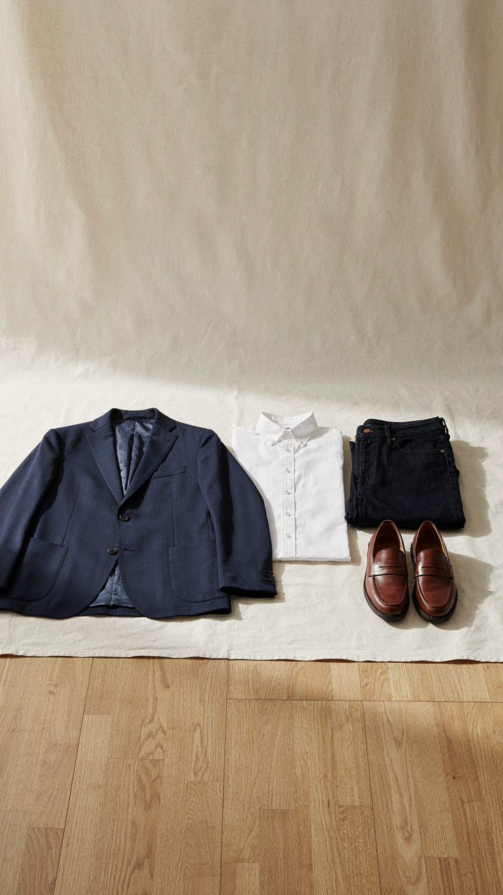 A small collection of key dressy casual clothes hangs in a minimalist wardrobe.