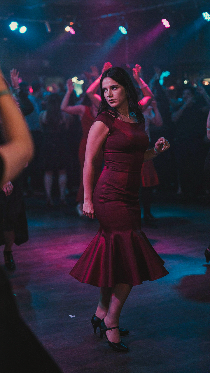 Woman pivoting on a dance floor in a fit and flare dress and stable shoes.