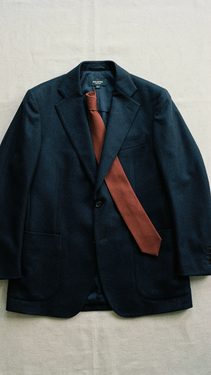 A rust-colored tie laid precisely on a classic navy suit jacket.