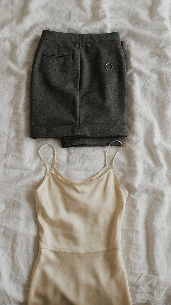 Tailored trousers and a fitted dress laid out, representing anchor pieces for an outfit.