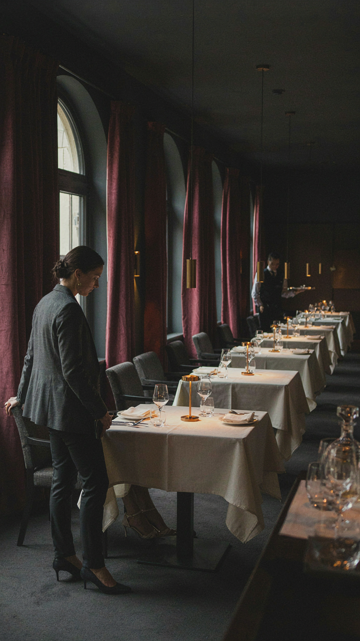 A woman discreetly observes other diners in an elegant restaurant.