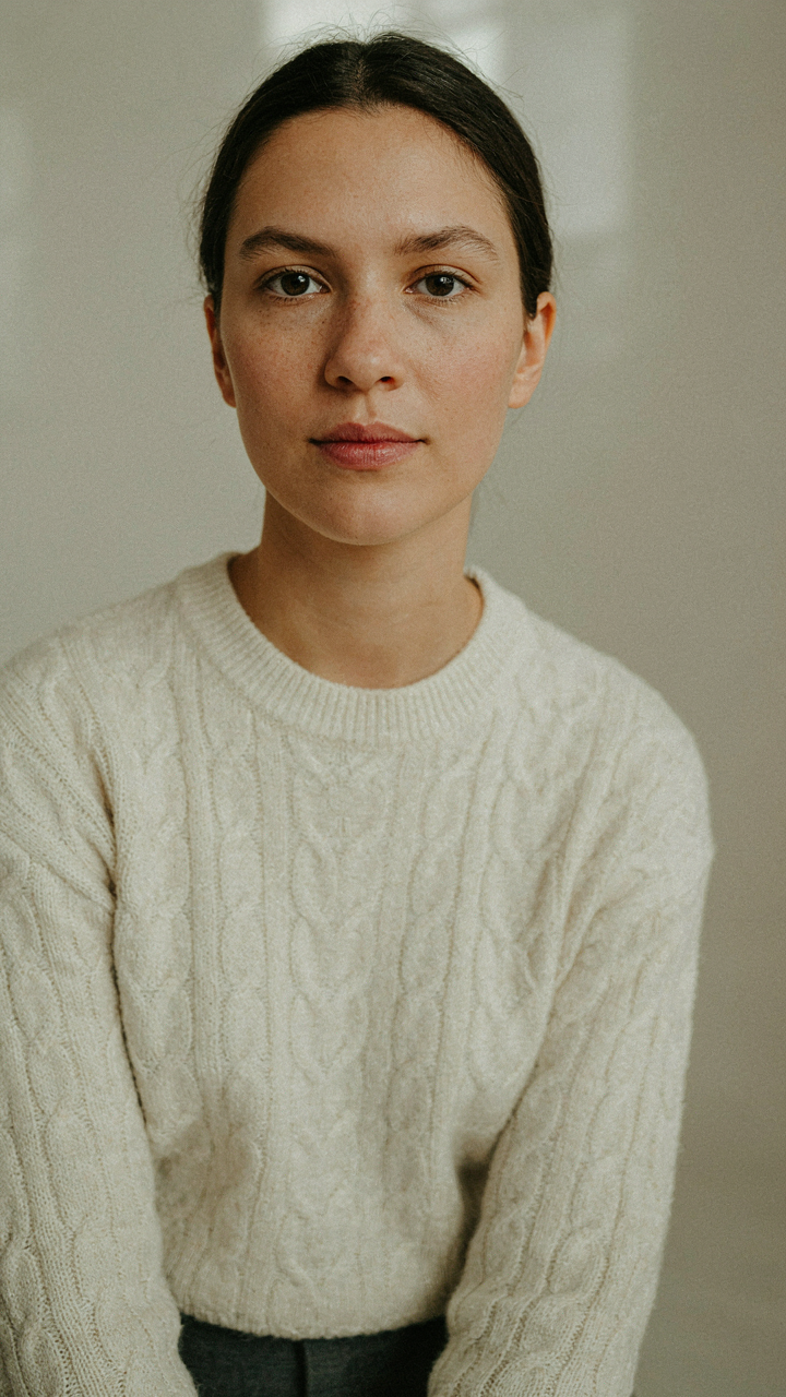 A person wears a cream sweater over charcoal pants, demonstrating visual contrast.