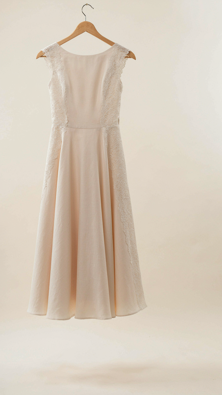 A midi-length cotton dress with a structured lace panel hangs on a hanger.
