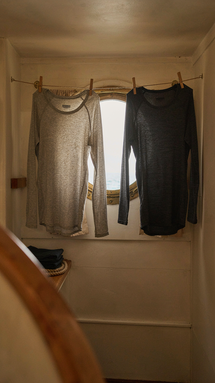 Two technical base layer shirts, one merino, one synthetic, drying in a ship cabin.