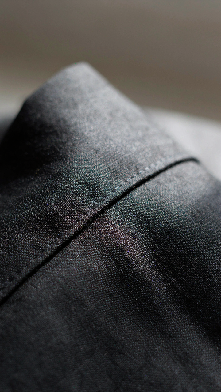 A close-up shows the tight stitching and rich texture of wool crepe fabric.