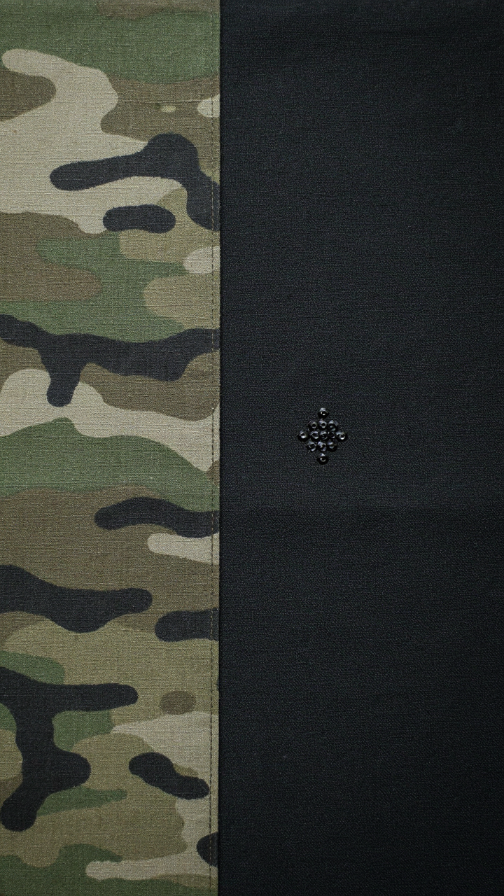 Military camouflage fabric next to dark fabric with a small sequin cluster.