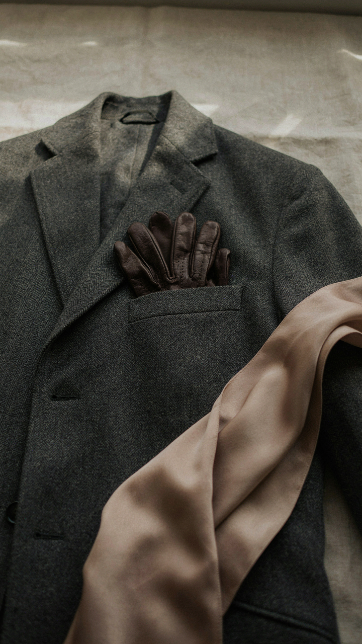 Elegant leather gloves tucked into a satin wrap on a structured wool coat.