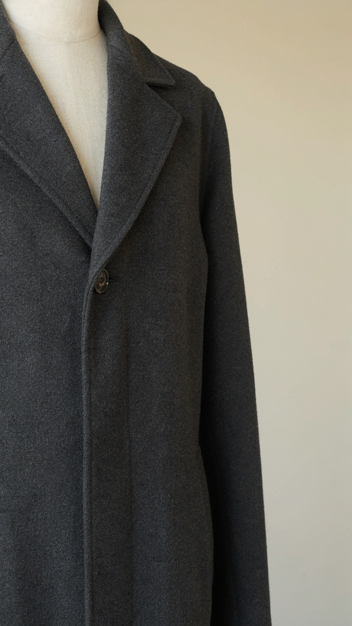 A close-up of a high-quality charcoal wool blend winter coat with flat seams.