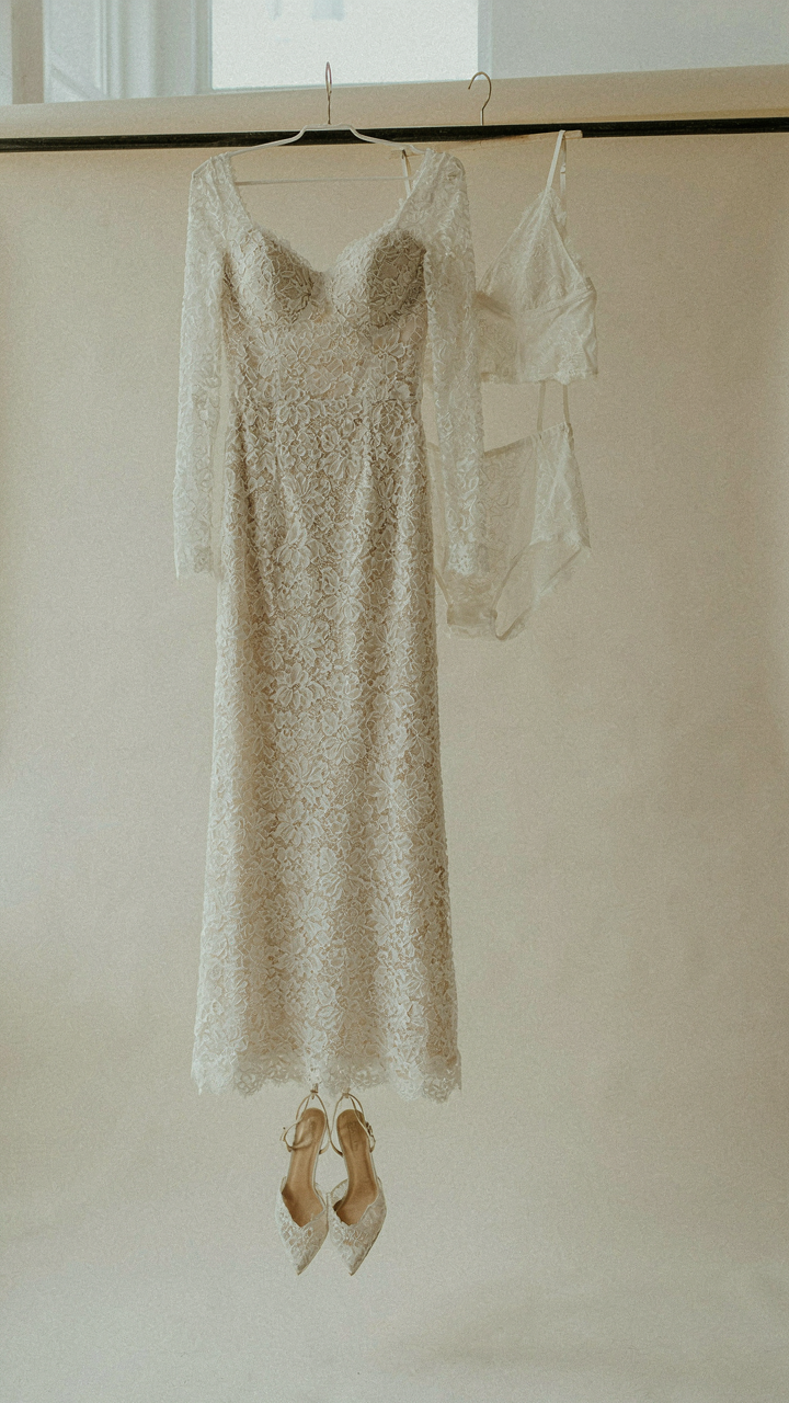 Monochromatic lace cocktail dress with matching shoes on a minimalist rack.