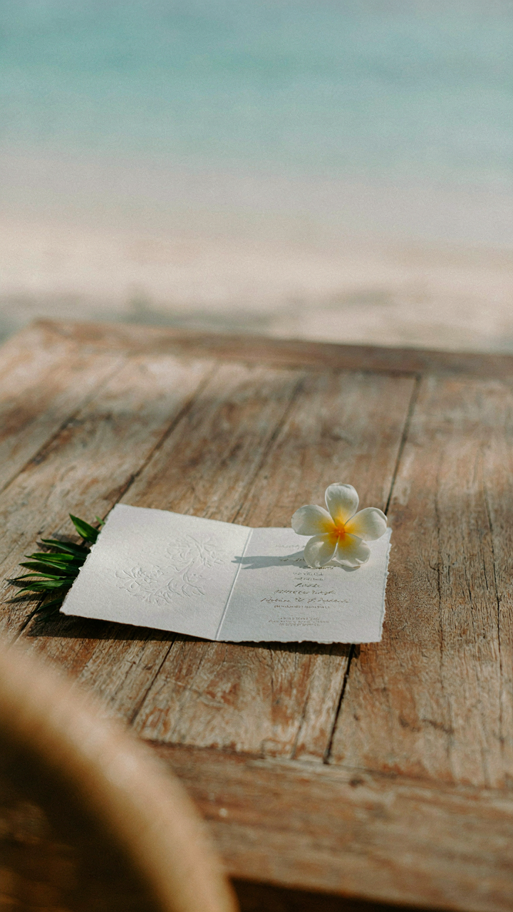 An open wedding invitation stating 'resort formal' with a tropical flower.