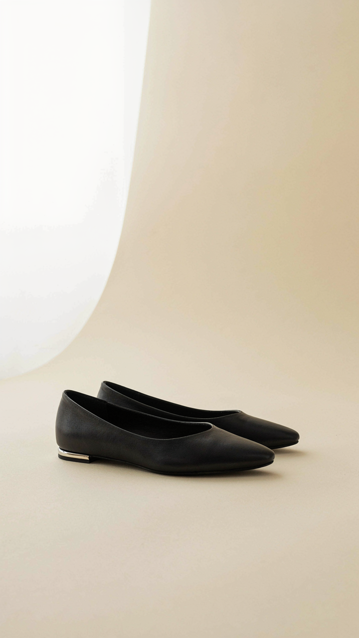 Sleek, black, pointed-toe leather ballet flats with metallic detail.