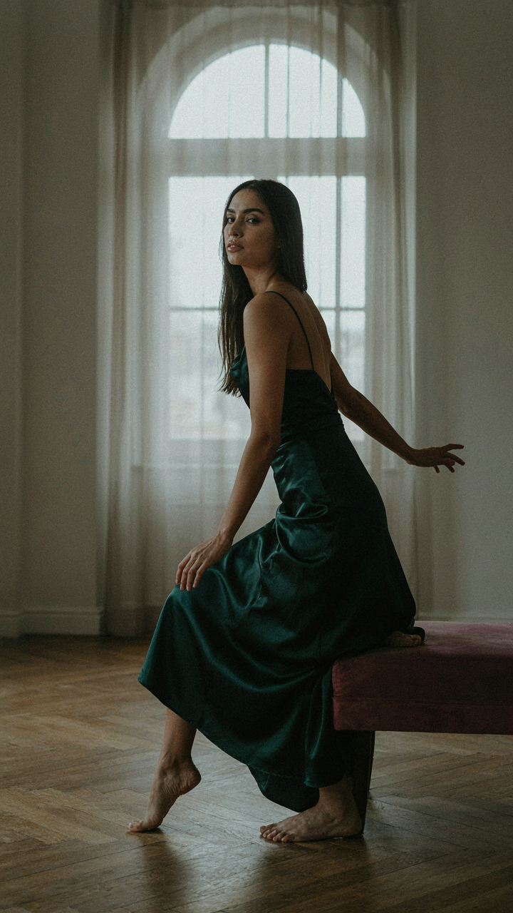 A woman in an evening gown pivots her body in a dynamic, flowing pose.