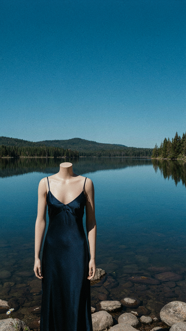 A navy dress stands out against a blue lake, showing colors that blend with nature.