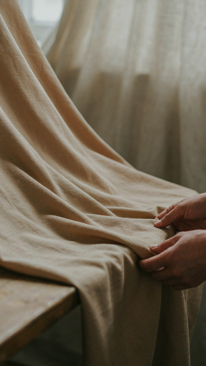 Hands gently test the luxurious drape of a wool crepe fabric.