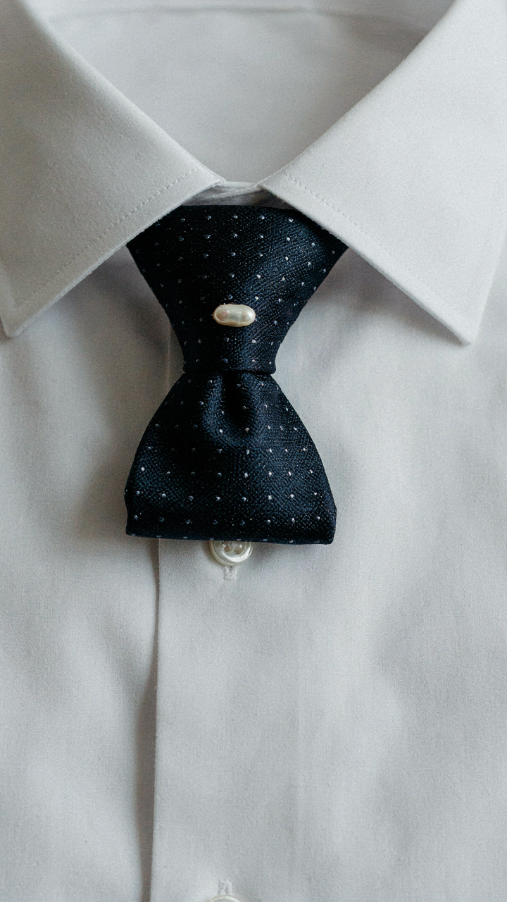 Perfectly tied formal knot of a silk tie on a white shirt.