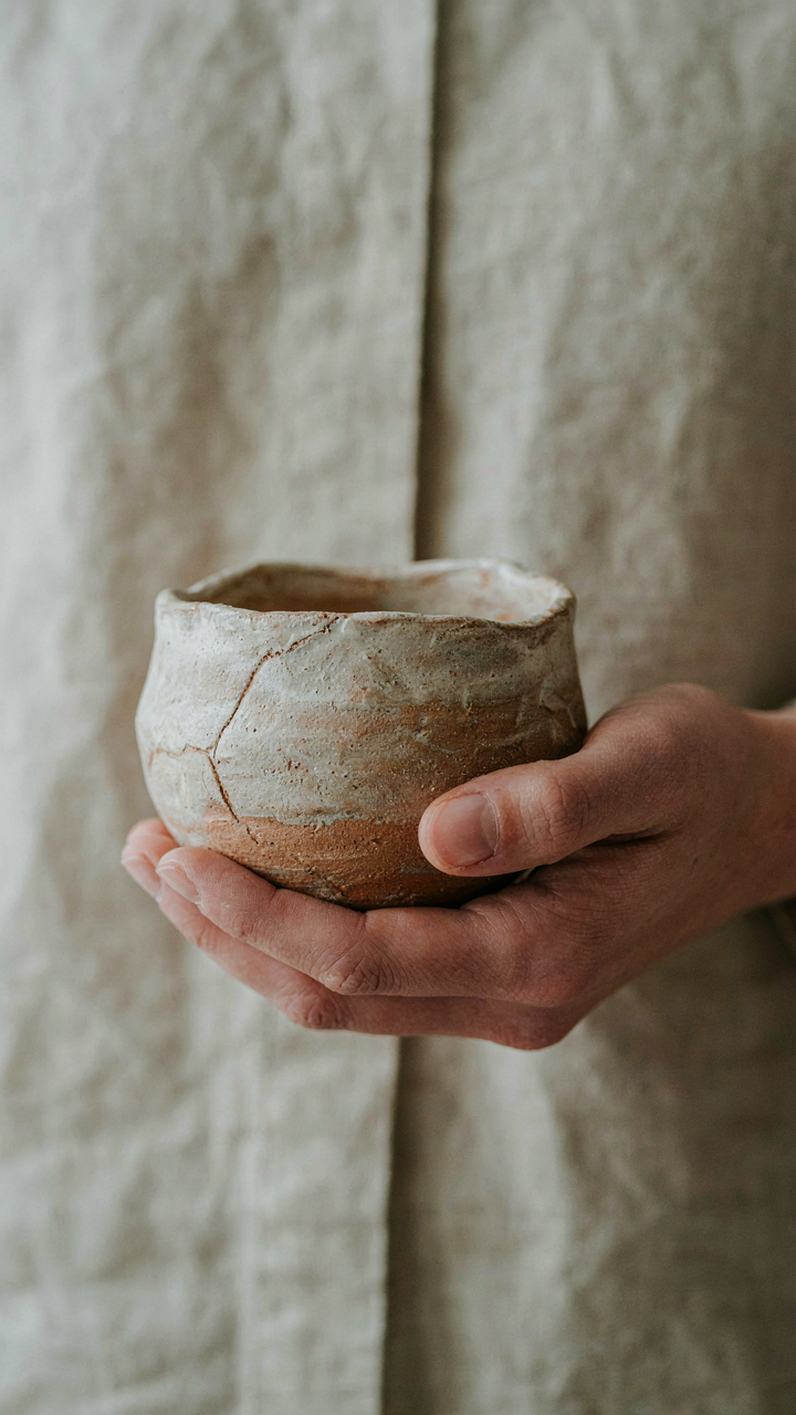A hand holds a unique handcrafted ceramic piece, showing curated detail.