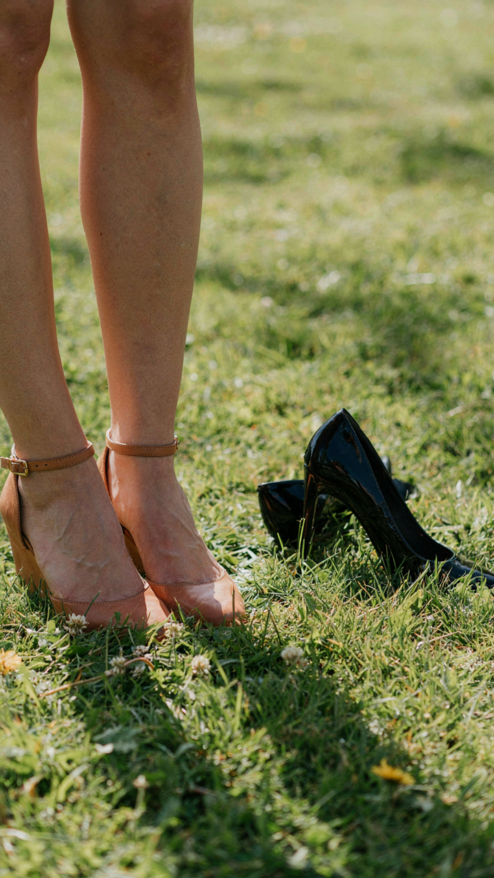 Wedges are stable on soft grass next to stiletto heels that have sunk.