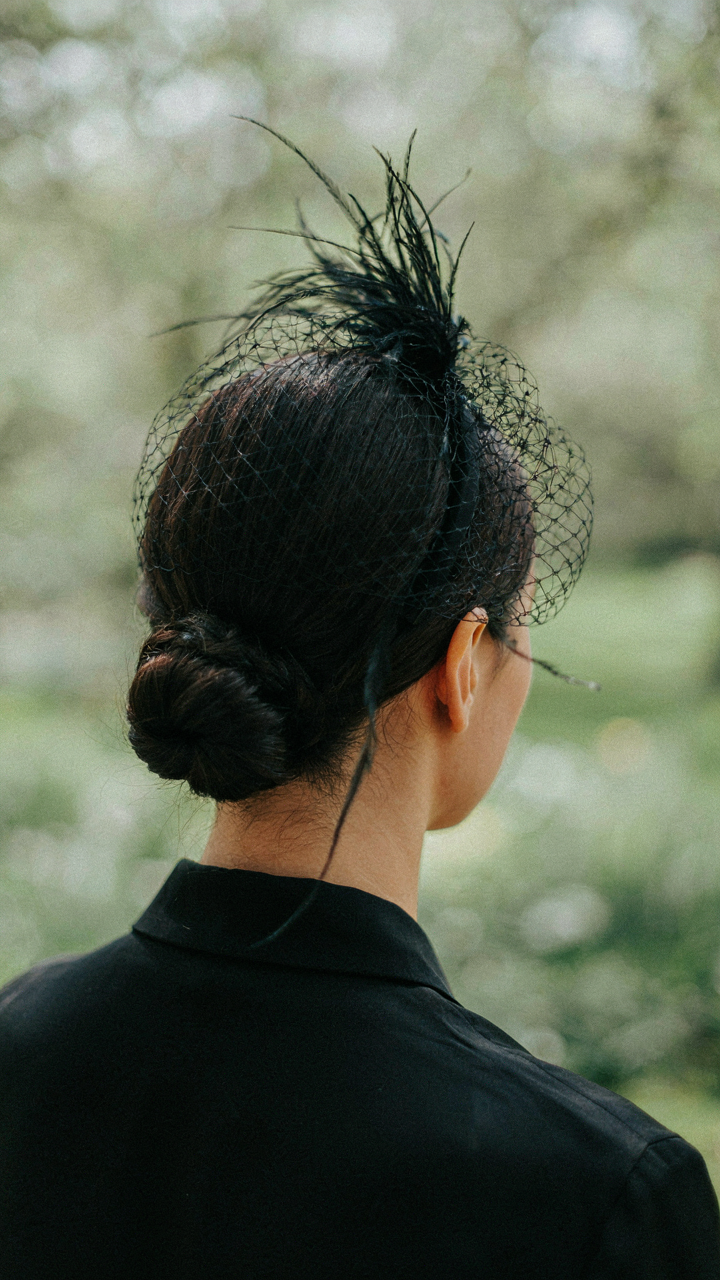 A delicate black fascinator pinned to a woman's styled hair.