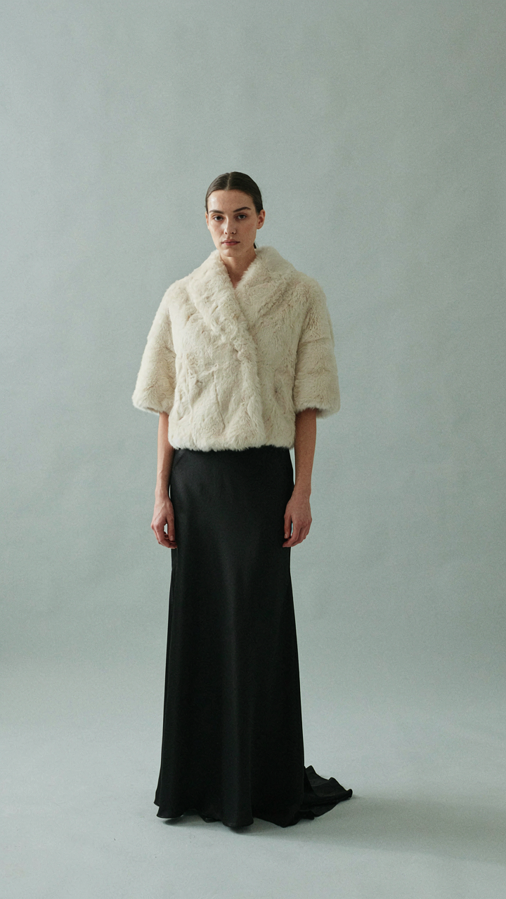Woman standing confidently in a structured faux fur wrap evening piece.