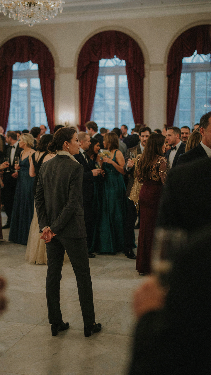 A person thoughtfully observing a diverse crowd at a formal event.