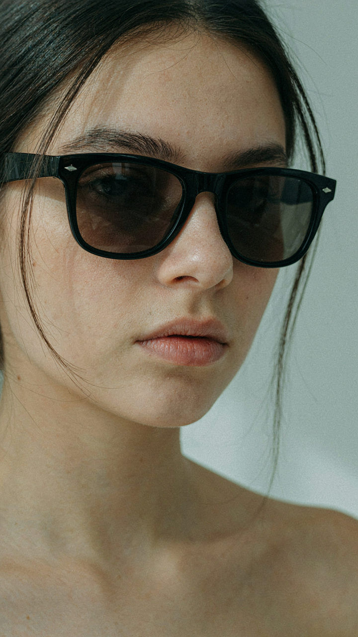 A round face wearing angular Wayfarer-style sunglasses, showing balanced proportions.