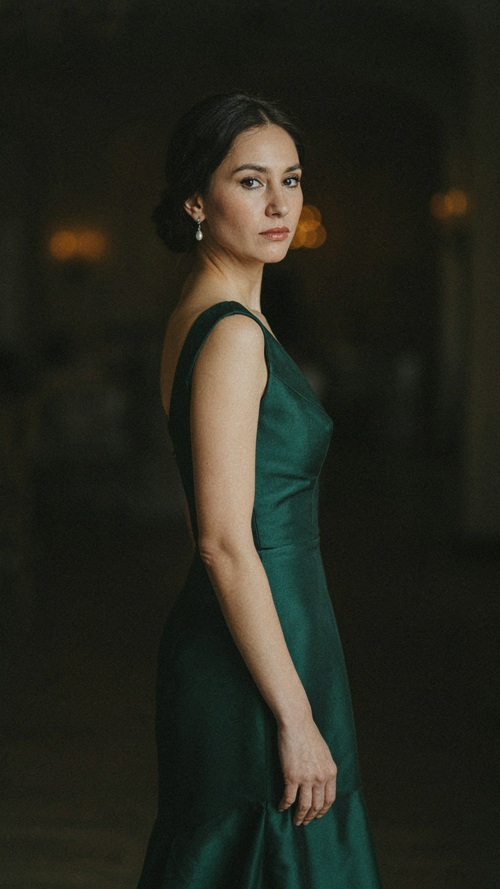 A woman in a jewel-toned structured silk evening cape at a formal event.