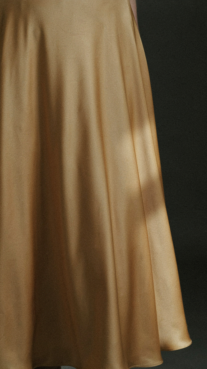 A close-up of a gold satin skirt showing its luminous sheen.