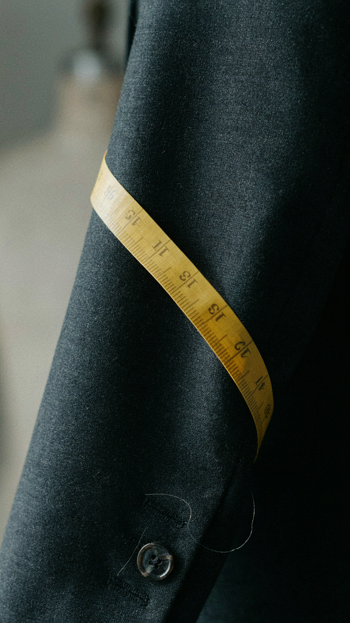 Close up of high quality wool fabric on a tailored blazer sleeve with a measuring tape.