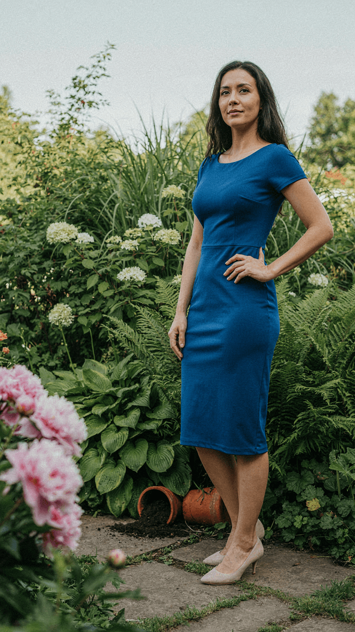 A confident woman in a bold dress stands in a garden.