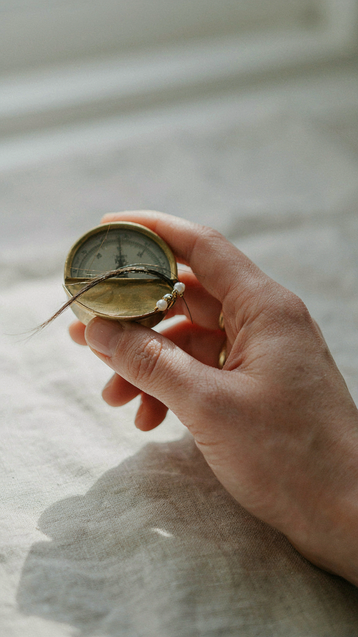 A hand balances a delicate hair clip on a strand of fine hair.