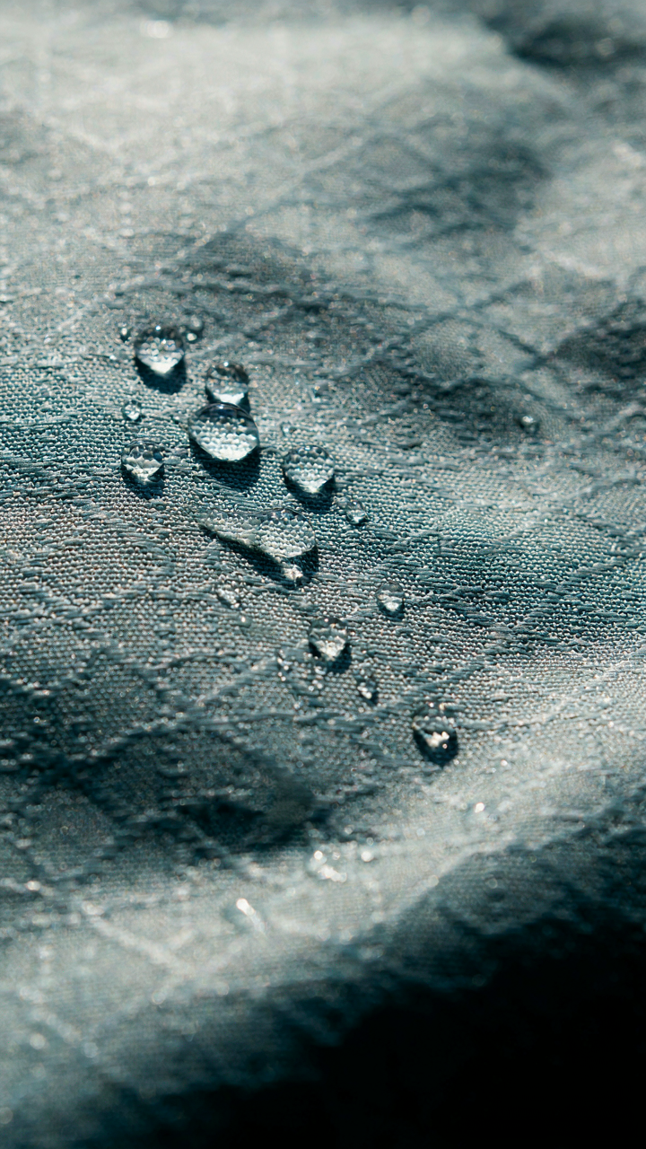 Water beads on a tightly woven synthetic fabric, showing its quick-dry properties.