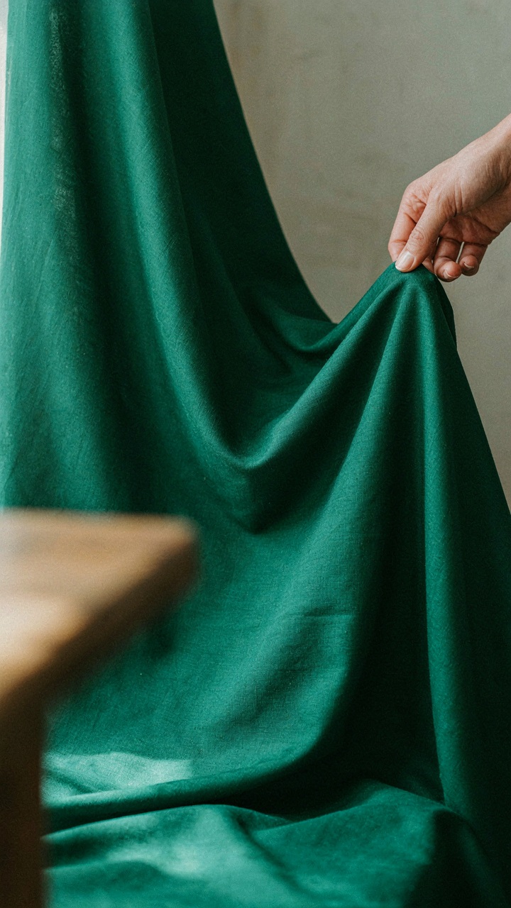 A hand touches a luxurious, weighty fabric, showing its quality and drape.