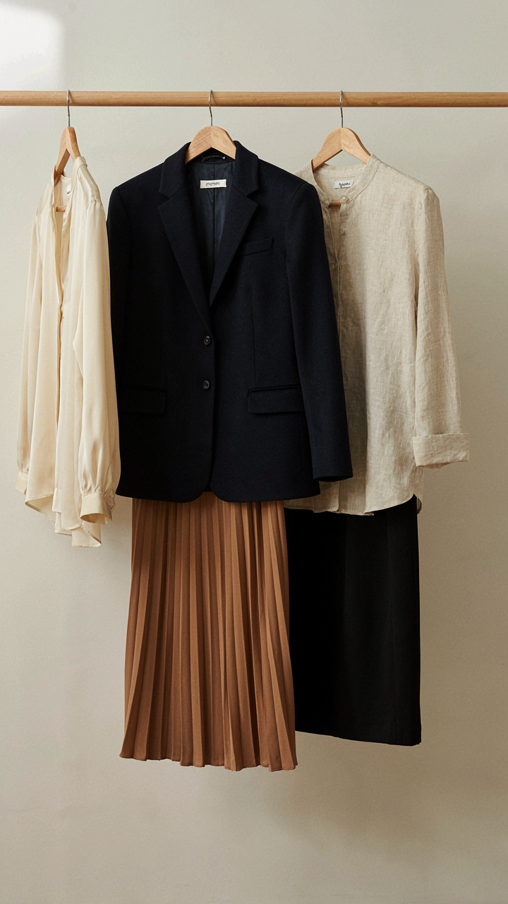 A navy blazer hangs next to blouses and skirts, ready for reuse.