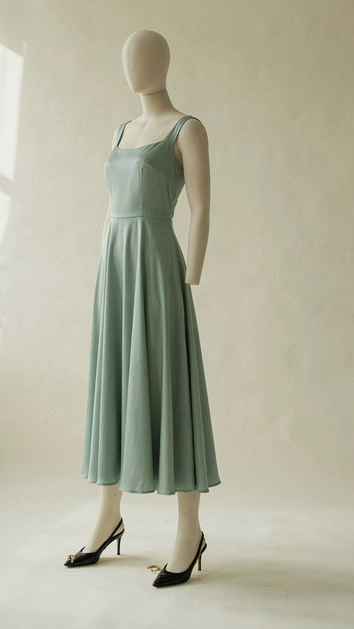 A mannequin wearing a midi-length dress, illustrating balanced proportions from shoulder to hem.