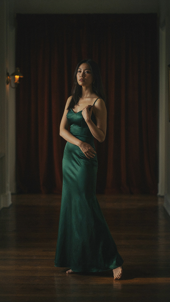 A woman in an evening gown is poised, as if about to step forward.