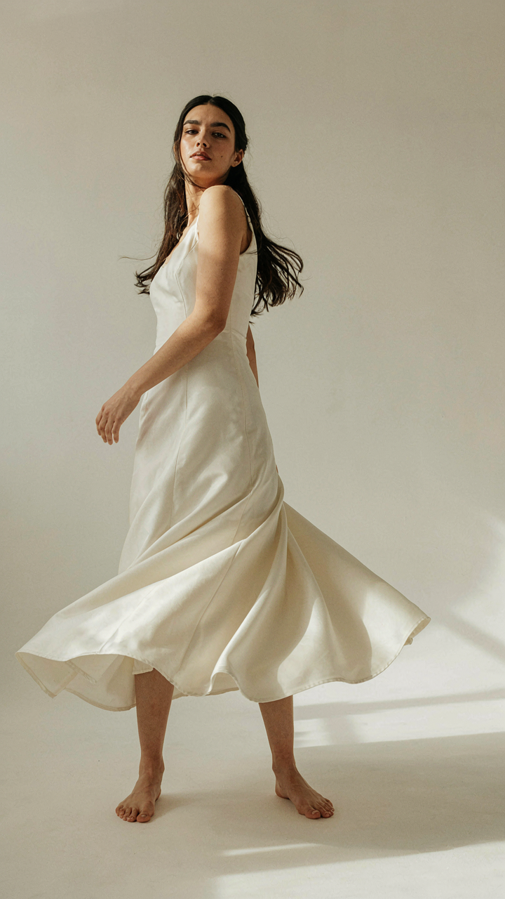 Woman in a long dress twists, showing kinetic energy in the fabric.