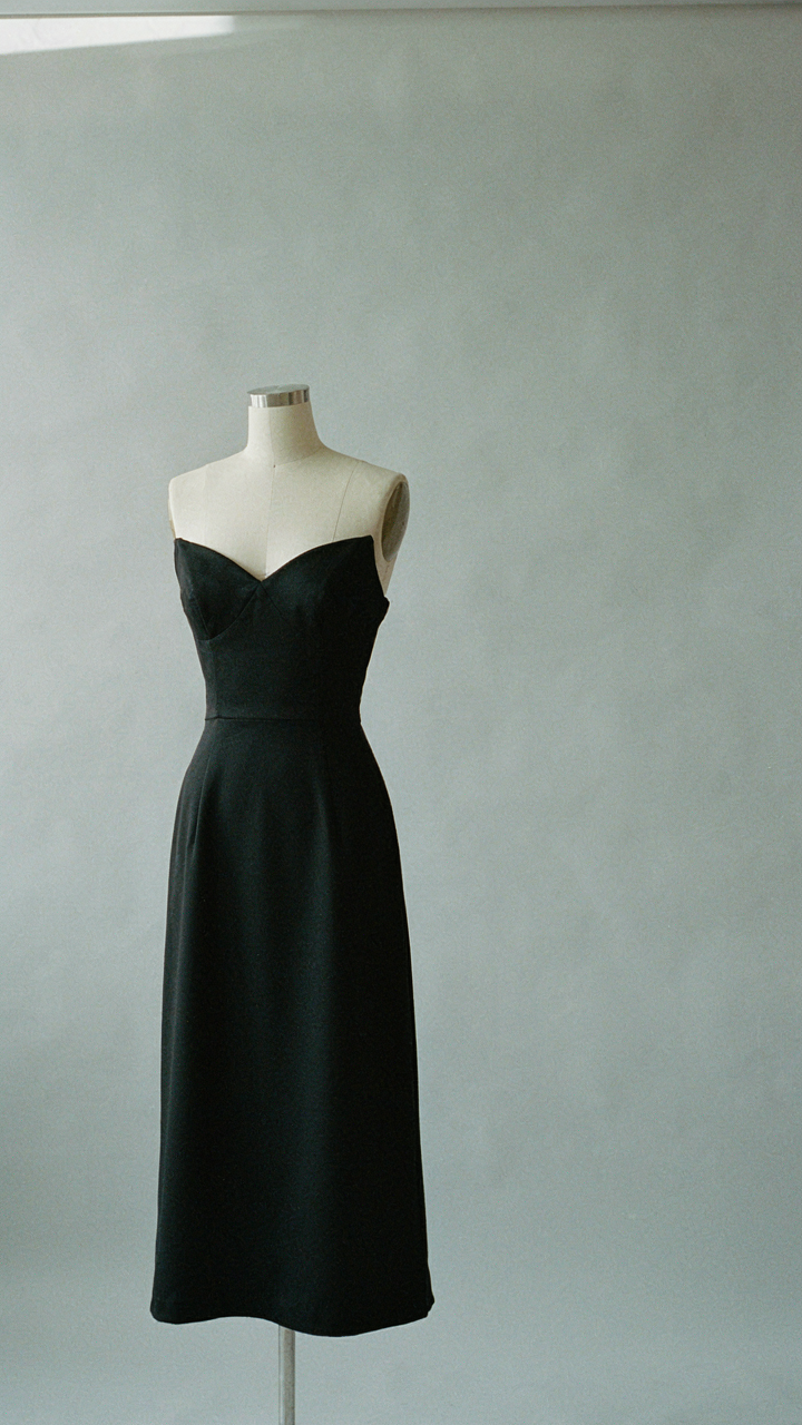 A timeless, well-cut black cocktail dress on a simple display form.
