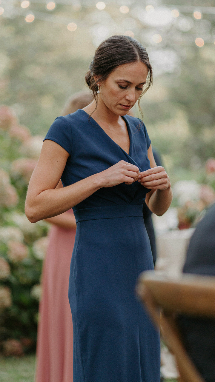 A woman wears a merino wool base layer under her sapphire blue wedding guest dress.