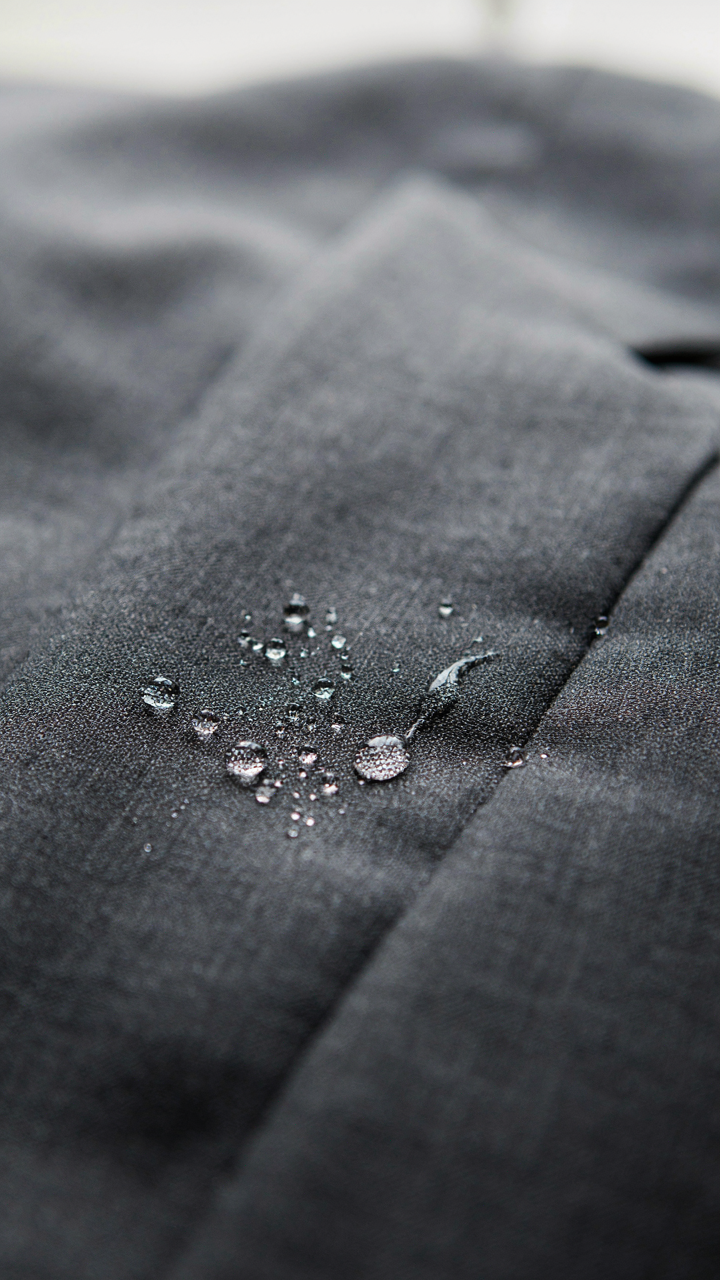 A high-performance suit fabric repels water, showing its resilience to humidity.